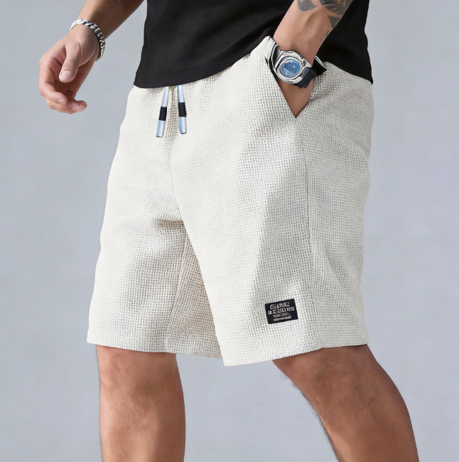 Person wearing beige shorts with a brand label on a gray background