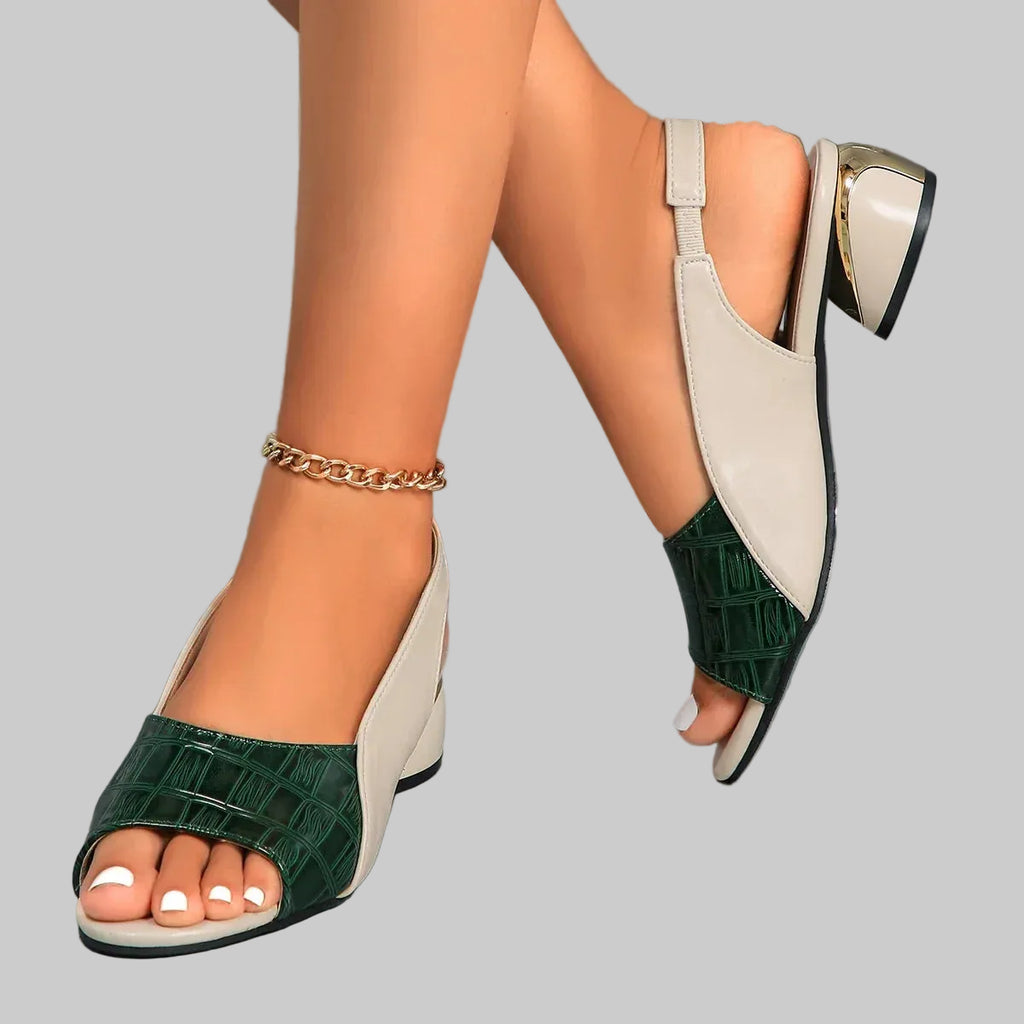 Green and beige high-heeled sandals worn by a person on a gray floor.