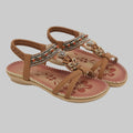 Pair of brown sandals with decorative straps on a white background