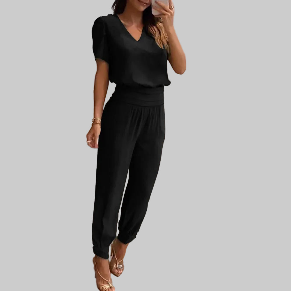 Woman taking a mirror selfie wearing a black outfit in a modern interior setting.