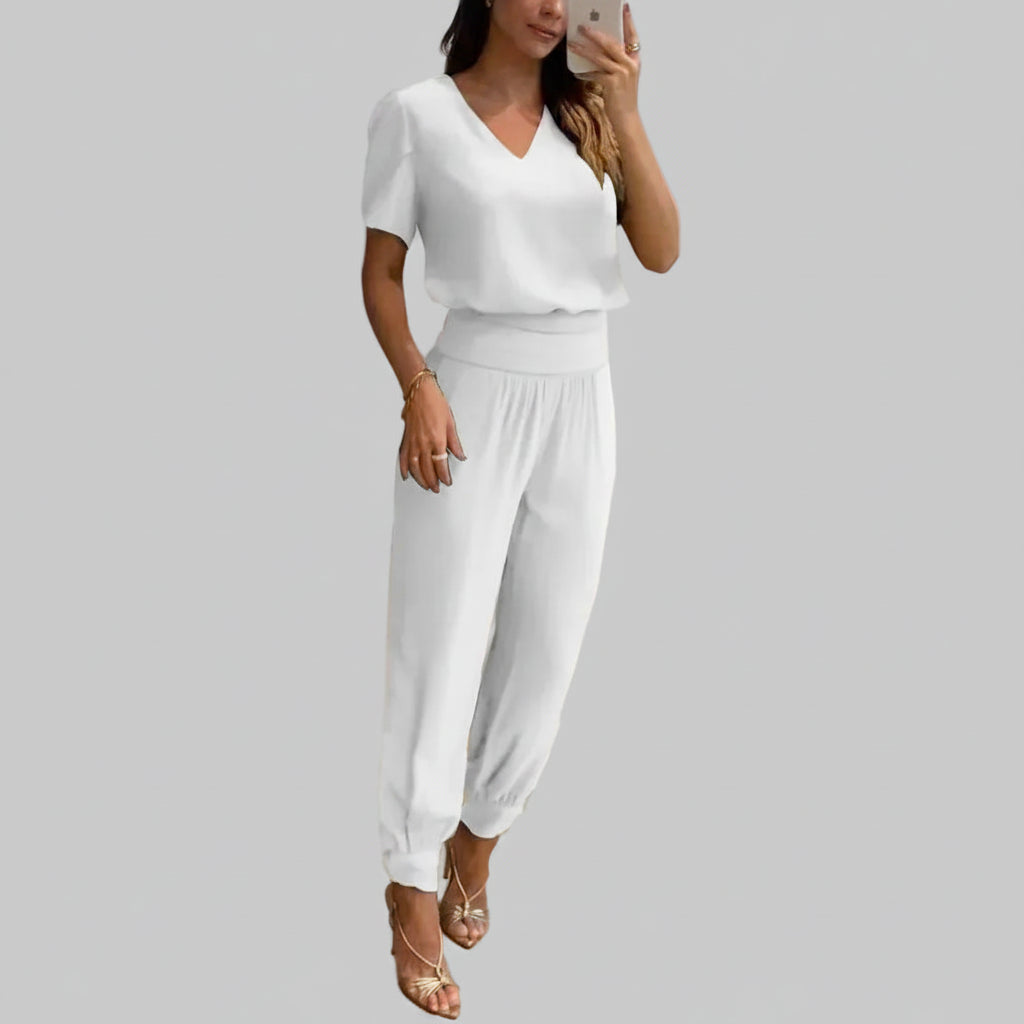 Woman wearing a white outfit taking a mirror selfie in an indoor setting.