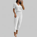 Woman wearing a white outfit taking a mirror selfie in an indoor setting.