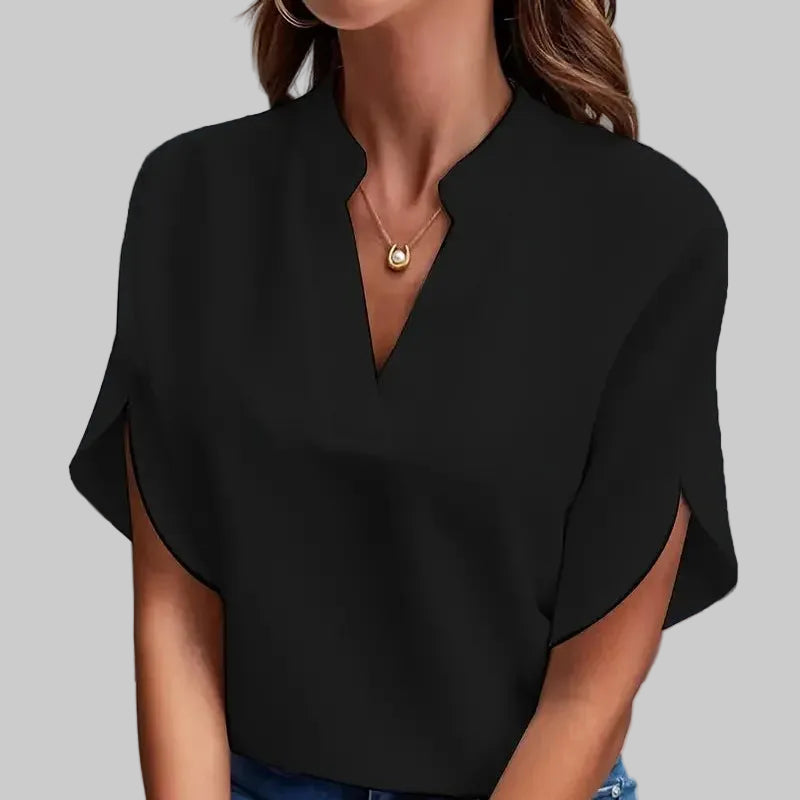 Person wearing a black blouse and blue jeans against a gray background