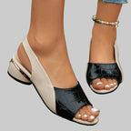 Black and white open-toe sandals worn by a person on a wooden surface.