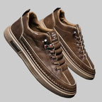 Pair of brown leather shoes on a reflective surface with a gray background
