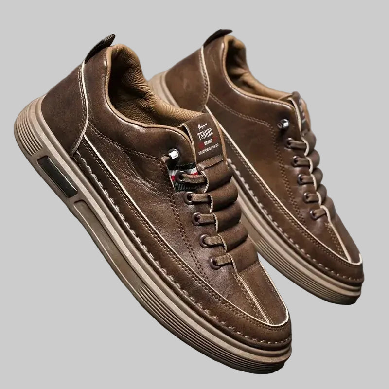 Pair of brown leather shoes on a reflective surface with a gray background