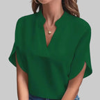 Person wearing a green blouse and blue jeans against a neutral background