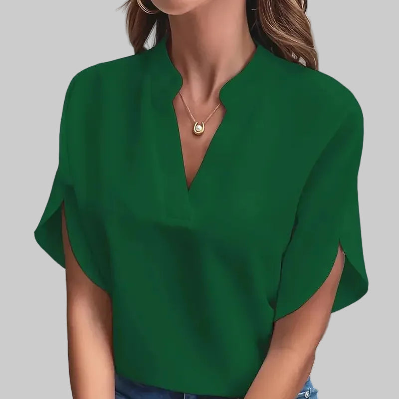 Person wearing a green blouse and blue jeans against a neutral background