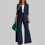 Woman in a navy suit holding a green handbag in an indoor setting