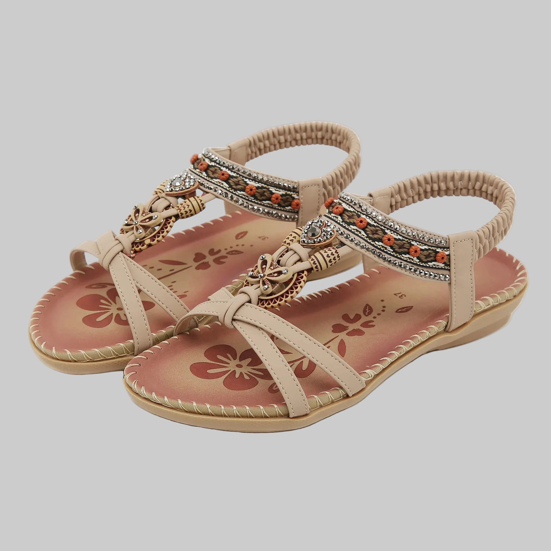 Beige sandals with decorative straps and floral patterns on a white background