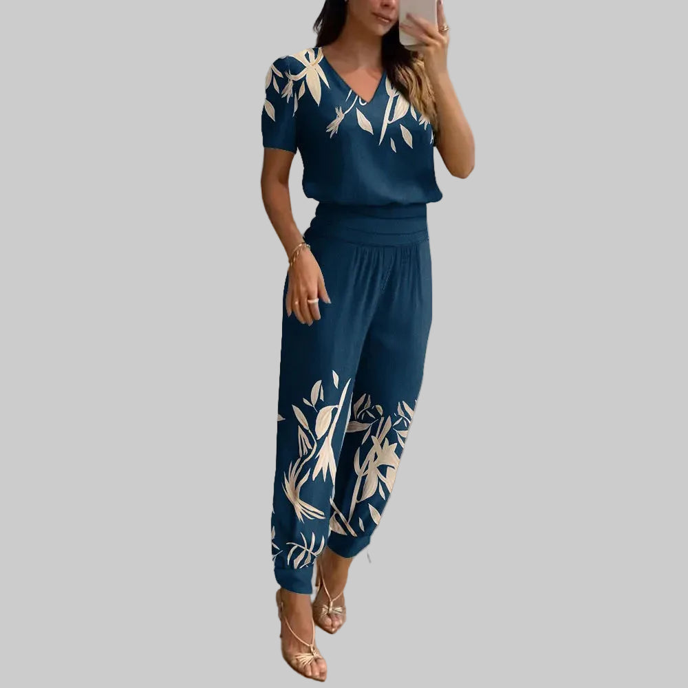 Woman taking a mirror selfie wearing a blue outfit with white floral patterns in a modern room.