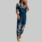 Woman taking a mirror selfie wearing a blue outfit with white floral patterns in a modern room.