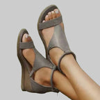 Gray sandals worn on feet with a blurred green background