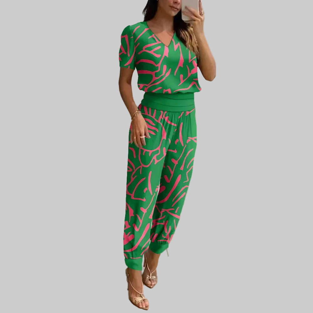 Woman taking a mirror selfie wearing a green and pink patterned outfit in a modern room.
