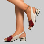 White sandals with red accents worn by a person on a gray background