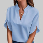 Woman wearing a light blue blouse and jeans against a gray background