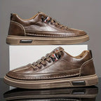 Brown leather sneakers on a reflective surface with a gray background