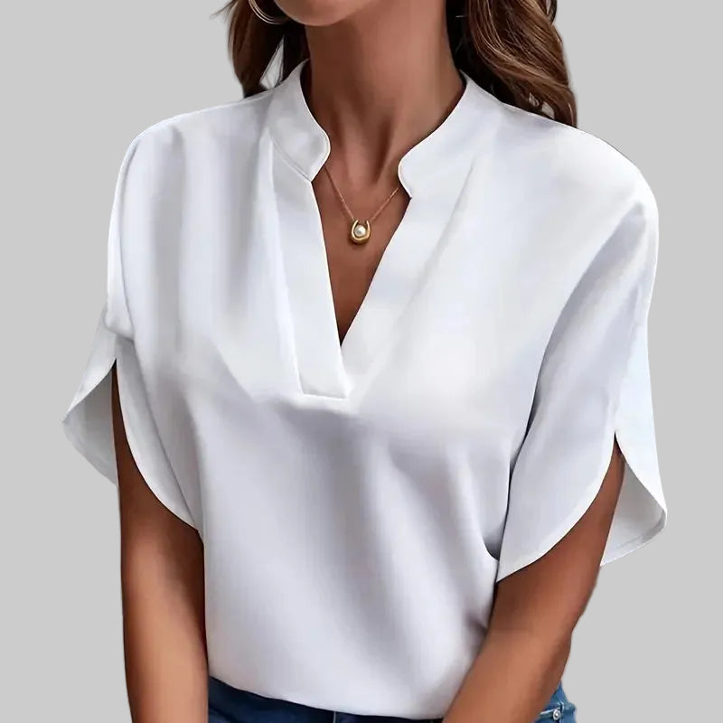Woman wearing a white blouse and blue jeans against a gray background