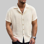 Man wearing a beige short-sleeve button-up shirt on a white background
