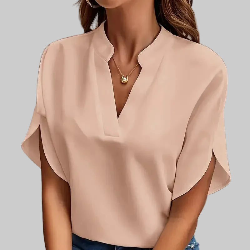 Woman wearing a beige blouse and blue jeans against a gray background