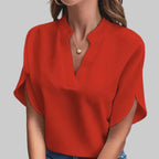 Person wearing a red blouse and blue jeans against a gray background
