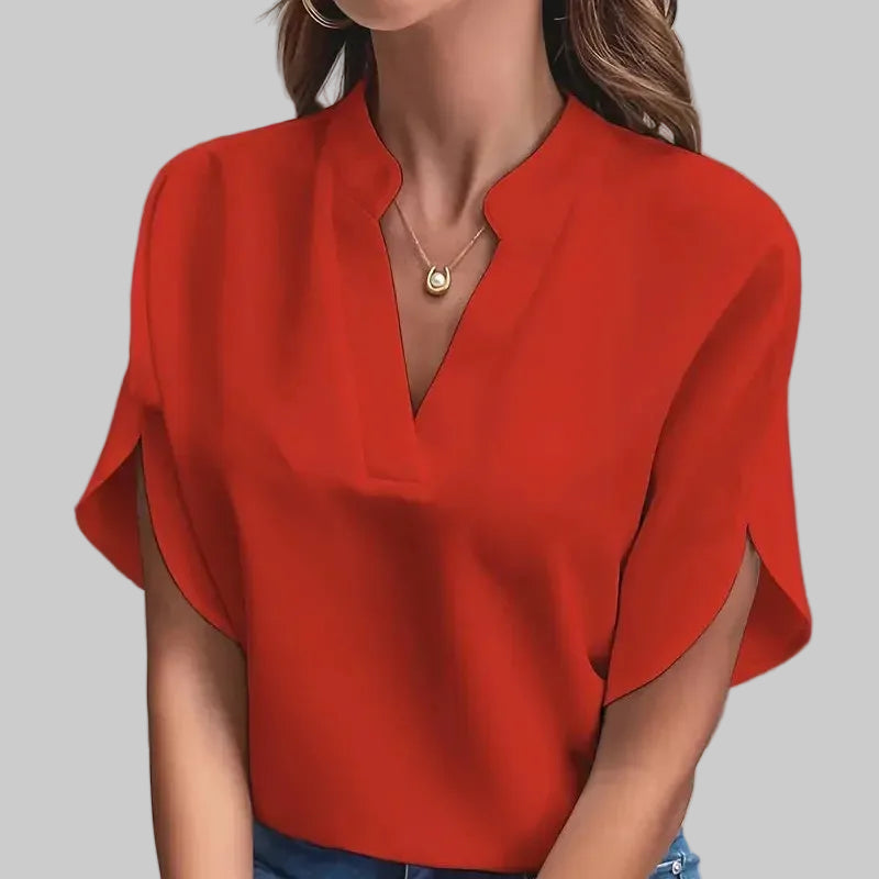 Person wearing a red blouse and blue jeans against a gray background