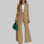 Woman wearing a beige suit with a teal handbag in an indoor setting