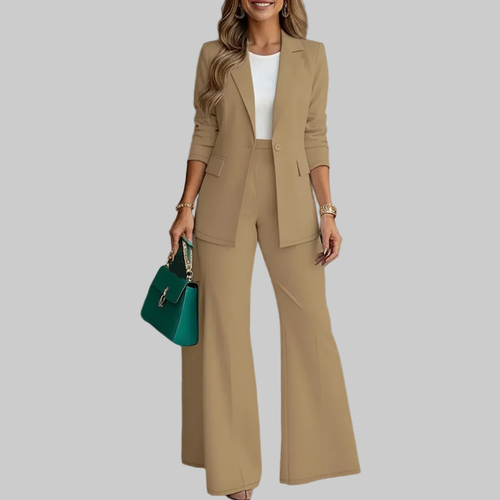 Woman wearing a beige suit with a teal handbag in an indoor setting