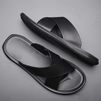 Black slide sandals on a gray background
