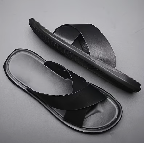 Black slide sandals on a gray background