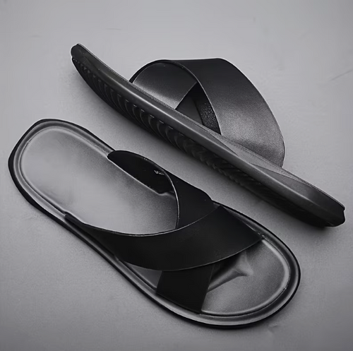 Black slide sandals on a gray background